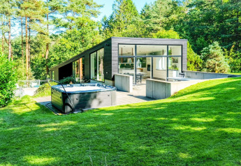 Modernes Ferienhaus in Ebeltoft, Dänemark, mit großen Fenstern, Whirlpool und üppigem grünen Garten.