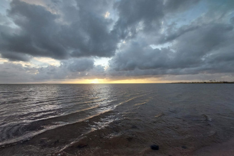 Sonnenuntergang über dem Meer bei Secluded Harbor Cottage in Dänemark mit dramatischen Wolken.
