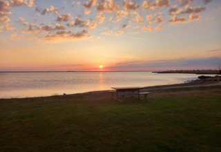 Sonnenuntergang am Wasser mit Picknicktisch auf Wiese vor Secluded Harbor Cottage in Dänemark.
