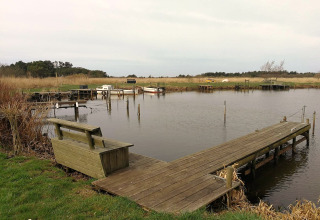 Houten steiger en bank bij Secluded Harbor Cottage in Denemarken, met rustig water en natuur.