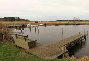 Billede af en træbrygge og bænk ved Secluded Harbor Cottage i Danmark med både og fredelig natur.