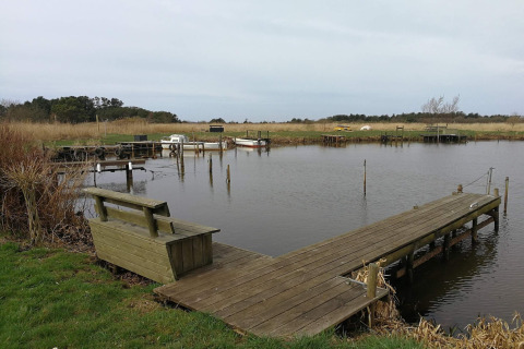 Houten steiger en bank bij Secluded Harbor Cottage in Denemarken, met rustig water en natuur.