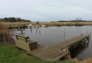Houten steiger en bank bij Secluded Harbor Cottage in Denemarken, met rustig water en natuur.