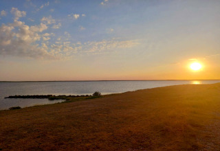 Zonsondergang boven rustig water gezien vanaf Secluded Harbor Cottage in Denemarken, gouden lucht en kust.