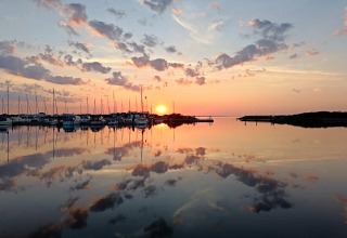 Zonsondergang boven rustig water bij Secluded Harbor Cottage in Denemarken, boten weerspiegeld.
