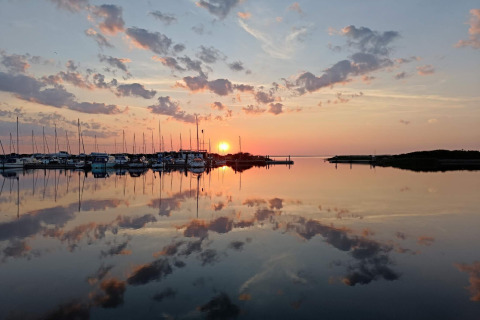 Sonnenuntergang am ruhigen Wasser bei Secluded Harbor Cottage in Dänemark mit reflektierten Booten.