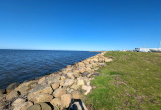 Kustzicht bij Secluded Harbor Cottage in Denemarken met blauwe lucht, boten en rotsen aan het water.