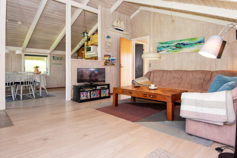 Wohnzimmer im Secluded Harbor Cottage in Dänemark mit Deckenbalken, Sofa, Tisch und Fernseher.