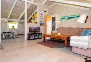 Woonkamer in Secluded Harbor Cottage in Denemarken met balkenplafond, tv, bank en houten tafel.