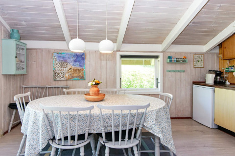 Gezellige eethoek in Secluded Harbor Cottage in Denemarken met ronde tafel, houten stoelen en decor.