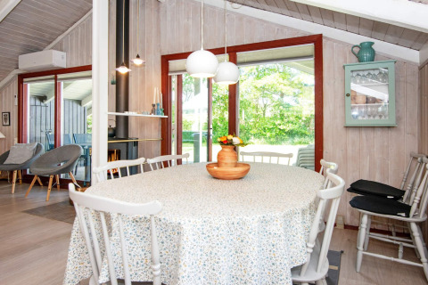 Lichte eetkamer bij Secluded Harbor Cottage in Denemarken met ronde tafel en uitzicht op de tuin.