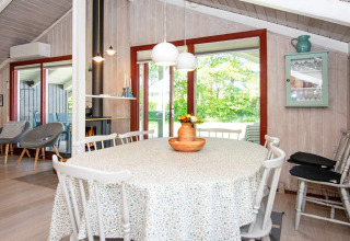 Helles Esszimmer in der Secluded Harbor Cottage in Dänemark mit Rundtisch, Holzmöbeln und Blick ins Grüne.