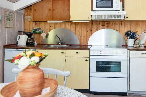 Gemütliche Küche im Secluded Harbor Cottage in Dänemark mit Holzverkleidung, Herd und Mikrowelle.