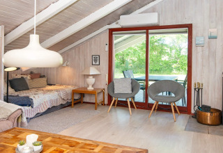 Woonkamer in Secluded Harbor Cottage, Denemarken, met schuine plafonds, bed, stoelen en tuinzicht.