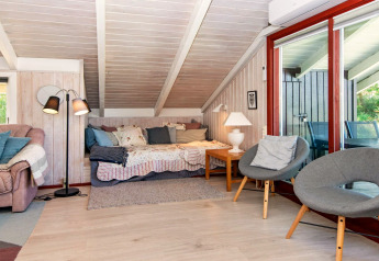 Hyggelig stue i Secluded Harbor Cottage med skrå loft, sovesofa, grå stole og store vinduer i Danmark.