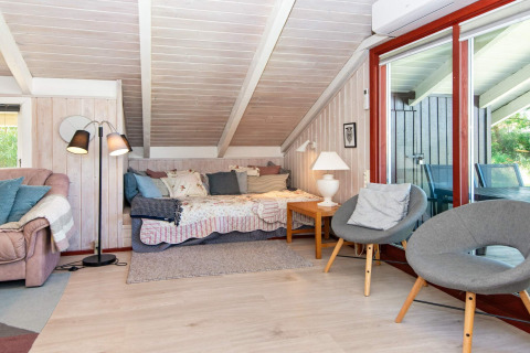 Gezellige woonkamer in Secluded Harbor Cottage, Denemarken, met slaapbank, grijze stoelen en grote ramen.