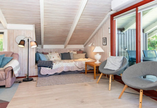 Gezellige woonkamer in Secluded Harbor Cottage, Denemarken, met slaapbank, grijze stoelen en grote ramen.