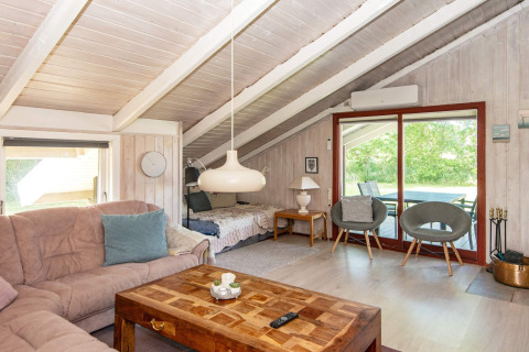 Woonkamer in Secluded Harbor Cottage, Denemarken, met bank, houten tafel en schuine plafonds.