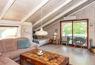 Woonkamer in Secluded Harbor Cottage, Denemarken, met bank, houten tafel en schuine plafonds.