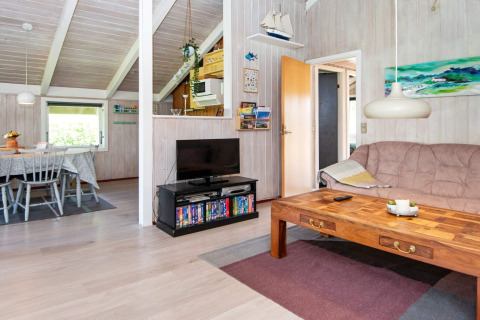 Woonkamer in Secluded Harbor Cottage, Denemarken, met houten tafel, bank, tv en eethoek.