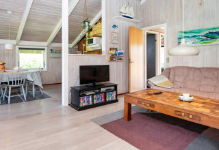 Woonkamer in Secluded Harbor Cottage, Denemarken, met houten tafel, bank, tv en eethoek.