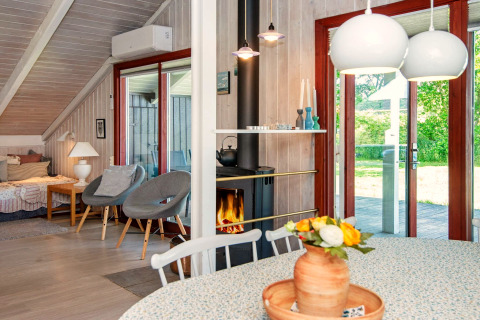 Licht en sfeervol lodge-interieur bij Secluded Harbor Cottage in Denemarken met haard, bloemen en tuinzicht.