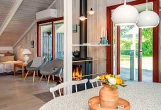 Licht en sfeervol lodge-interieur bij Secluded Harbor Cottage in Denemarken met haard, bloemen en tuinzicht.
