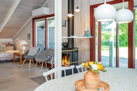 Licht en sfeervol lodge-interieur bij Secluded Harbor Cottage in Denemarken met haard, bloemen en tuinzicht.