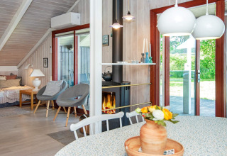 Licht en sfeervol lodge-interieur bij Secluded Harbor Cottage in Denemarken met haard, bloemen en tuinzicht.