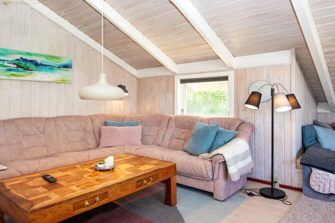Gemütliches Wohnzimmer in der «Secluded Harbor Cottage» mit Ecksofa, Holztisch, Lampen und Kunst.