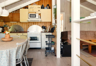 Gezellige keuken en woonkamer in Secluded Harbor Cottage, Denemarken, met eettafel en houten muren.