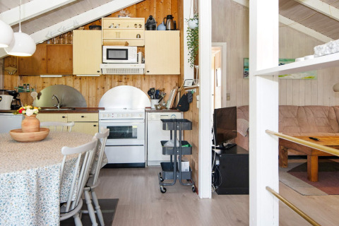 Gezellige keuken en woonkamer in Secluded Harbor Cottage, Denemarken, met eettafel en houten muren.