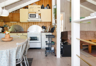 Gemütliche Küche und Wohnzimmer im Secluded Harbor Cottage, Dänemark, mit Esstisch und Holzdekor.