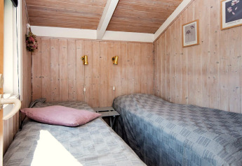 Lyst værelse med to enkeltsenge i Secluded Harbor Cottage, Danmark; hyggelig træbeklædning og vægkunst.