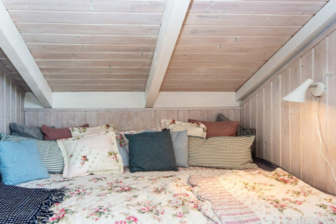 Gezellige slaapkamer in «Secluded Harbor Cottage» in Denemarken, met bloemenbeddengoed en veel kussens.