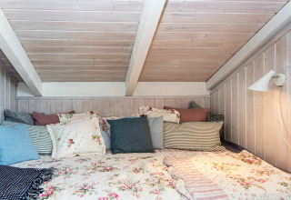 Gemütliches Schlafzimmer im «Secluded Harbor Cottage» in Dänemark, dekoriert mit vielen Kissen.