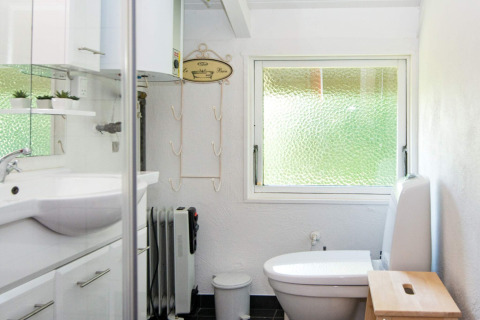 Helles Badezimmer im Secluded Harbor Cottage in Dänemark mit Fenster, Toilette und weißer Einrichtung.