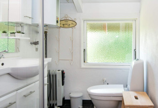 Helles Badezimmer im Secluded Harbor Cottage in Dänemark mit Fenster, Toilette und weißer Einrichtung.