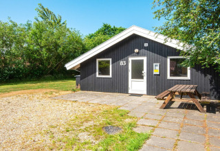 Gemütliches Ferienhaus Secluded Harbor Cottage in Dänemark mit Holztisch vor dem modernen schwarzen Haus.