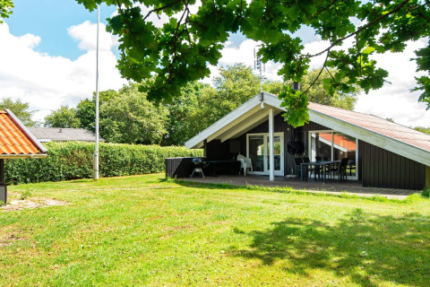 Urlaubslodge Secluded Harbor Cottage in Dänemark mit grüner Wiese, Terrasse und umgeben von Natur.
