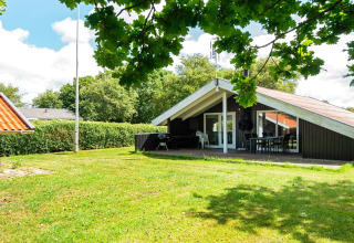 Urlaubslodge Secluded Harbor Cottage in Dänemark mit grüner Wiese, Terrasse und umgeben von Natur.