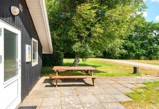 Terras van Secluded Harbor Cottage met picknickbank, bomen en een grindpad in Denemarken.