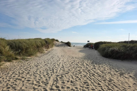 Zandpad door de duinen naar het strand bij het vakantiehuis in Blåvand, Denemarken, zonnige lucht.