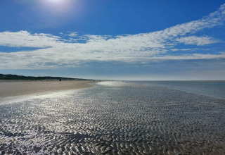Sonniger Strand bei Ebbe nahe dem 6-Personen-Ferienhaus in Blåvand, Dänemark, mit Himmel und Wolken.
