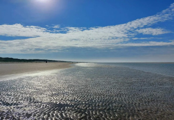 Playa soleada en marea baja cerca de casa de vacaciones para 6 personas en Blåvand, Dinamarca, con cielo y nubes.