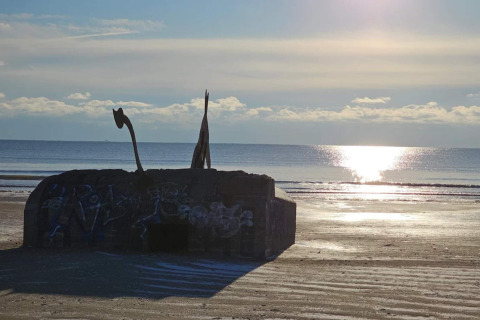 Foto di un vecchio bunker con graffiti sulla spiaggia di Blåvand, Danimarca, al tramonto sul mare.