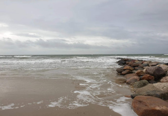 Épi rocheux s’avançant dans la mer agitée sous un ciel nuageux près de Blåvand, Danemark.