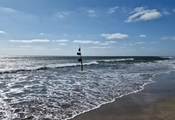 Vista de la playa desde la casa de vacaciones para 6 personas en Blåvand, Dinamarca, con mar y cielo azul.