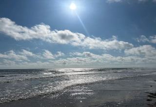 Zonnige dag op het strand bij het 6-persoons vakantiehuis in Blåvand, Denemarken, kalme zee en lucht.