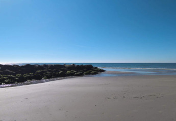 Zicht op een rustige strand en zee nabij het 6-persoons vakantiehuis in Blåvand, Denemarken, op een heldere dag.
